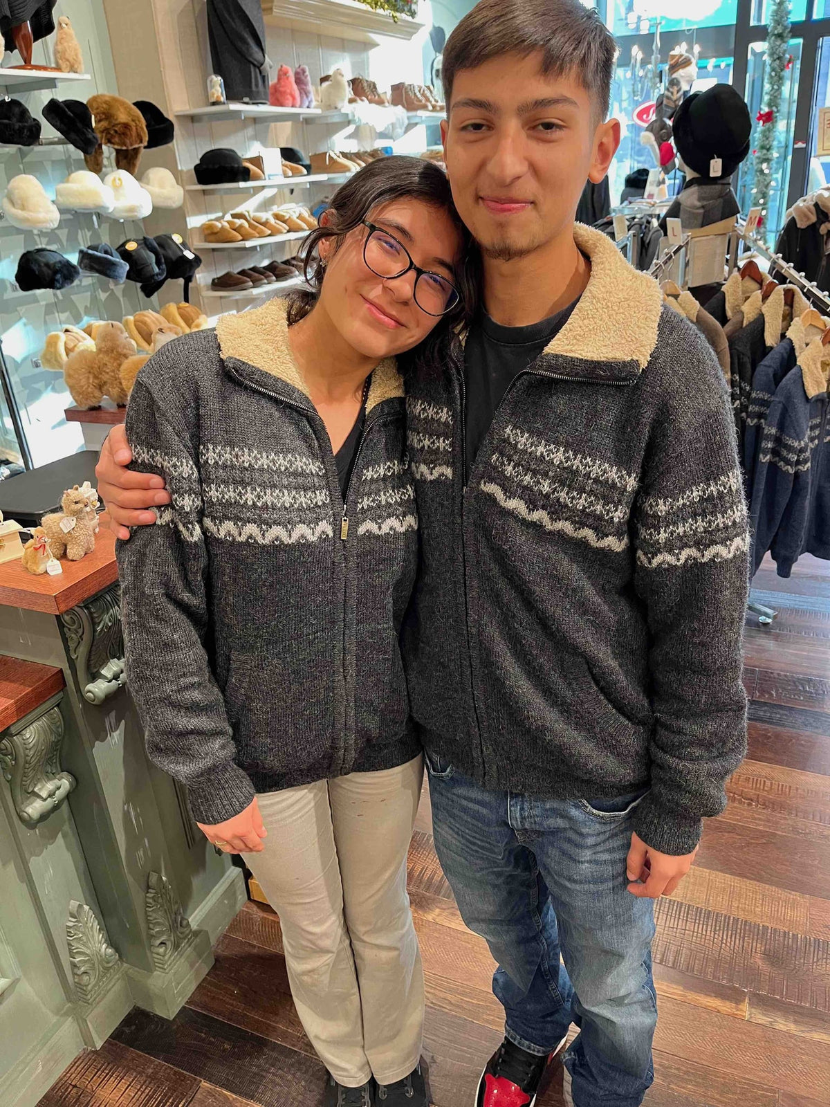 Couple wearing matching gray fleece-lined alpaca zip sweaters in store