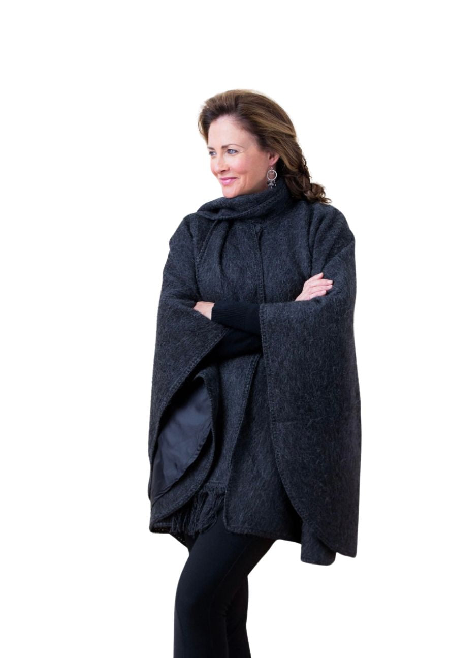 Woman in a charcoal alpaca cape with scarf, arms folded