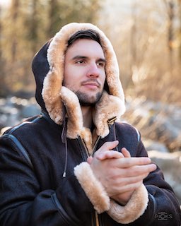 Man in a sheepskin bomber jacket with shearling hood up, close-up