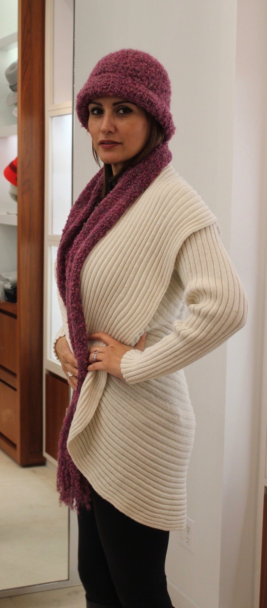 Woman wearing an ivory alpaca round sweater with purple hat and scarf