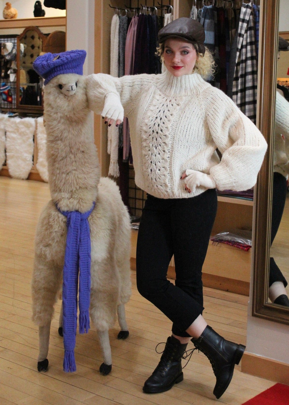 Woman in an ivory cable knit alpaca sweater beside an alpaca
