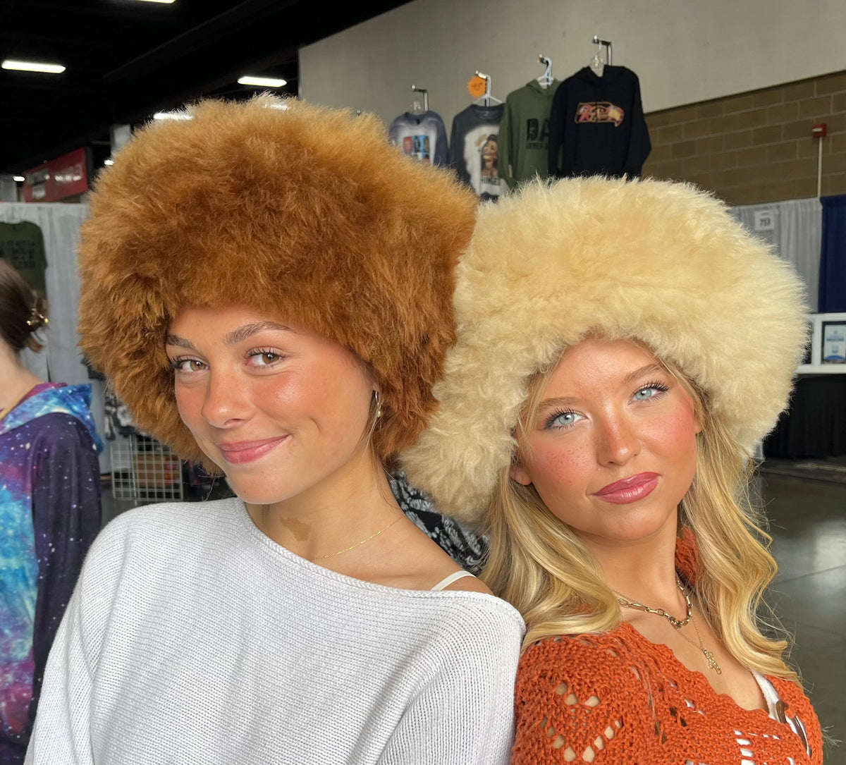 Two women in camel and cream baby alpaca fur hats