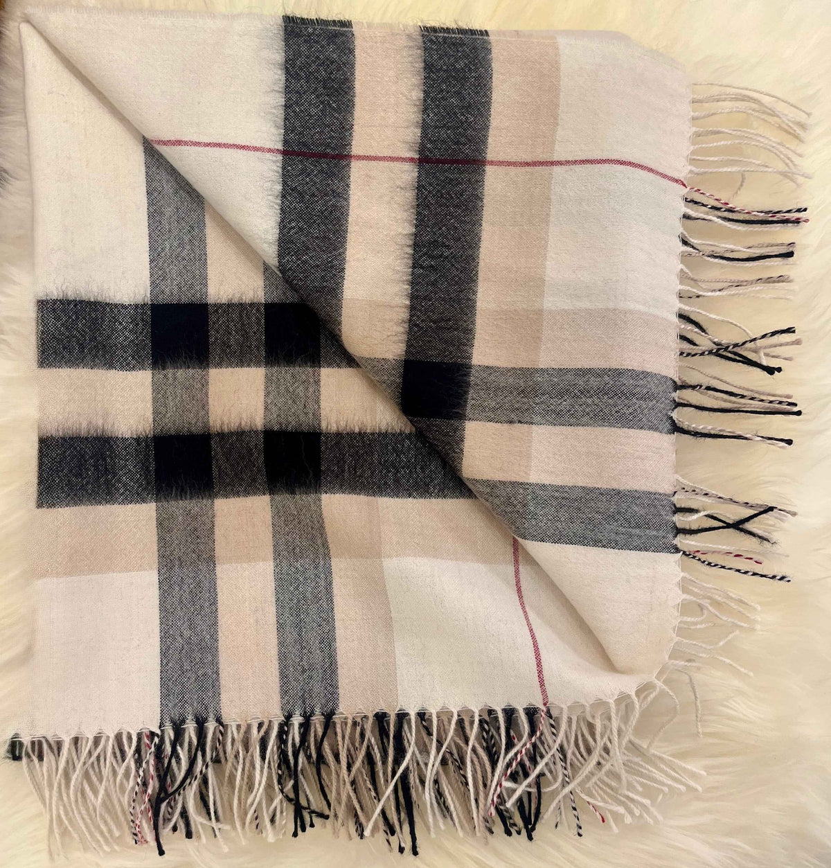 Folded ivory plaid baby alpaca throw with black stripes and fringe