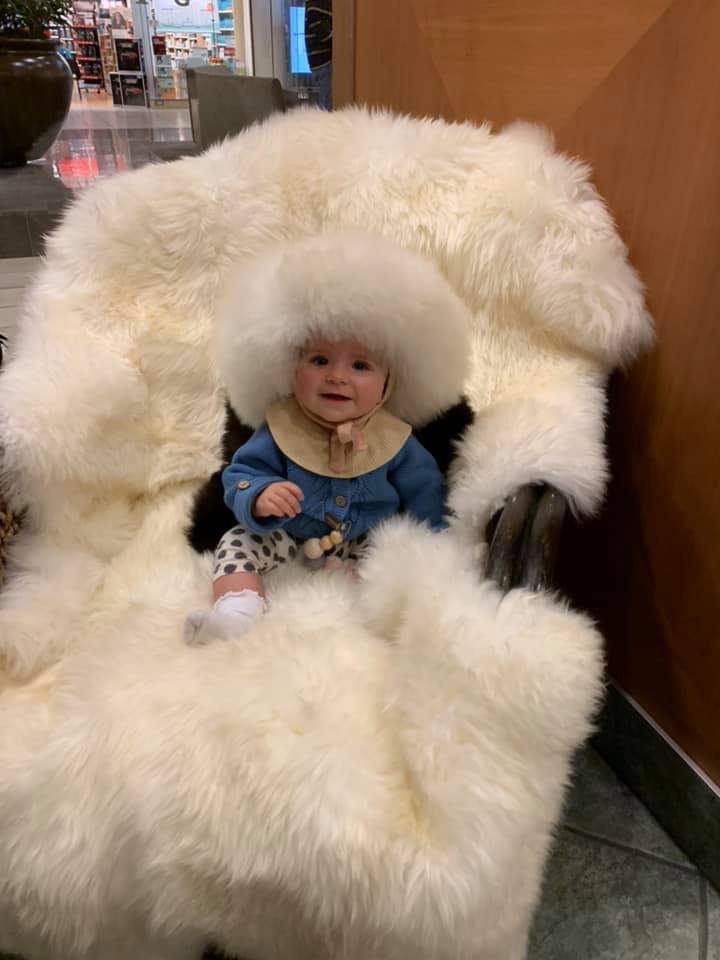 Baby seated in a stroller lined with a white sheepskin pelt