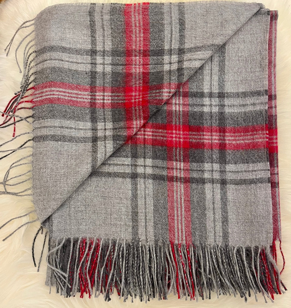 Folded grey and red tartan plaid alpaca throw with fringe