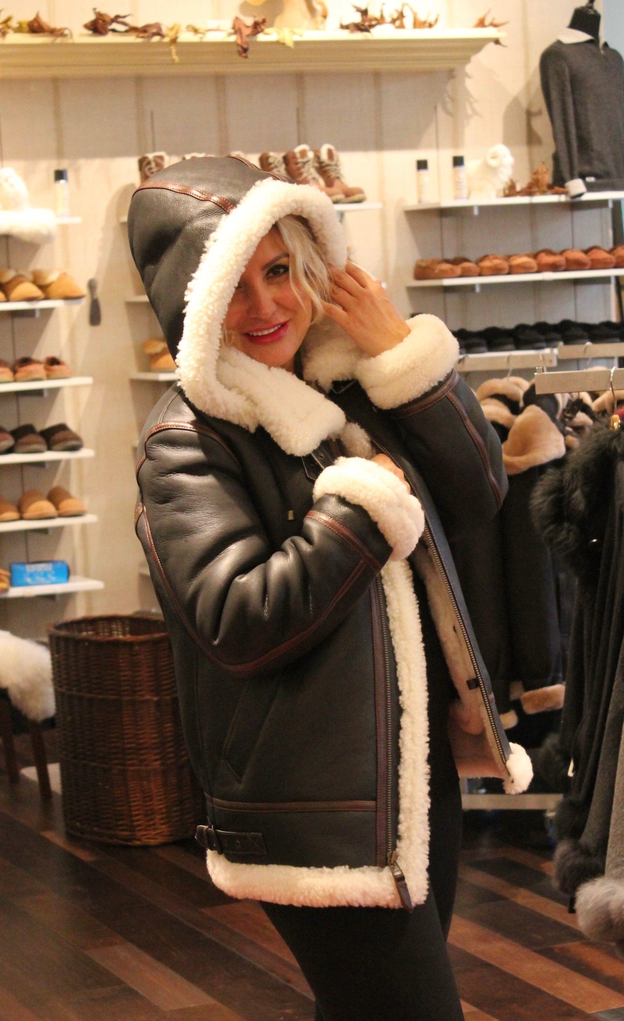 Woman trying on a men's hooded sheepskin bomber jacket in store