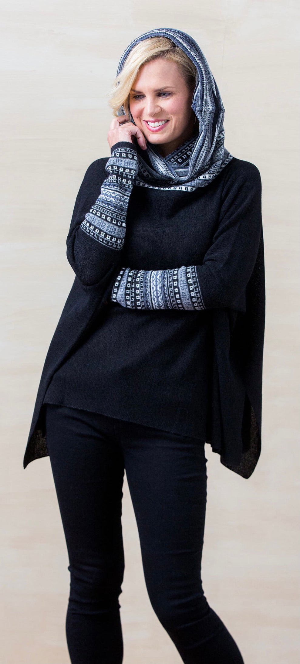 Woman wearing a black alpaca poncho sweater with patterned hood