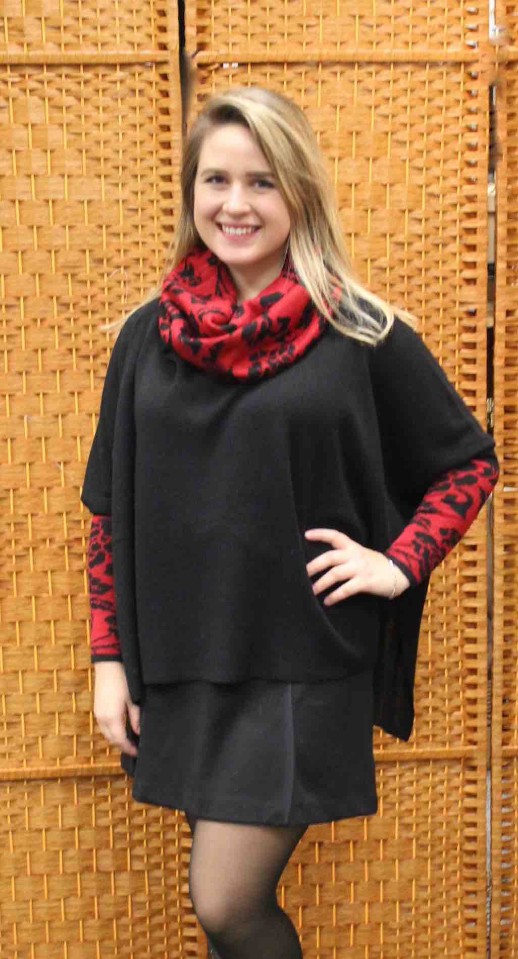 Woman wearing a black alpaca poncho sweater with red patterned cowl